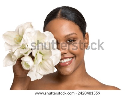 Beautiful young African American female model with stylish natural makeup covering half of face with delicate white flowers and looking at camera with toothy smile