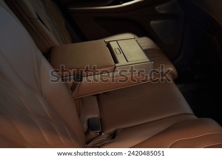 Armrest with cup holder inside. Leather comfortable white passenger seats and armrest. White leather interior of the luxury modern car. Modern car interior details. Rear passenger seats. Royalty-Free Stock Photo #2420485051