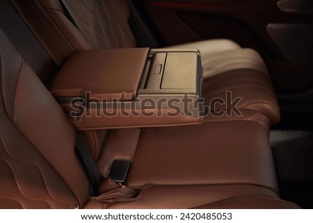 Armrest with cup holder inside. Leather comfortable white passenger seats and armrest. White leather interior of the luxury modern car. Modern car interior details. Rear passenger seats. Royalty-Free Stock Photo #2420485053