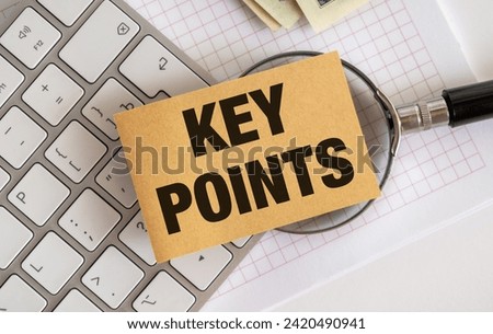 A well-lit photo featuring a brown notepad with Key Points written on it, set against a white keyboard and green money in the background. Ideal for stock photo use.