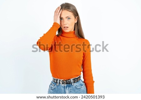 Embarrassed Young beautiful woman standing over white studio background with shocked expression, expresses great amazement, Puzzled model poses indoor