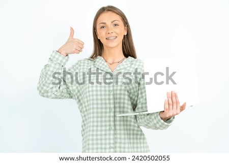 Beautiful attractive Young beautiful woman wearing green plaid pyjama hold netbook hand finger show thumb up