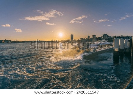 Ferry is leaving port while sunset at Milsons Point Wharf of Sydney NSW Australia Royalty-Free Stock Photo #2420511549
