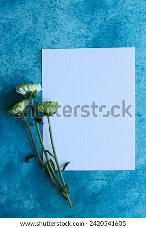 a white card with flowers on a blue background