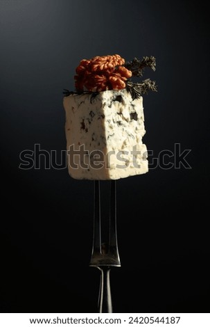 Blue cheese with walnuts and thyme on a fork.