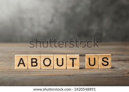 A row of wooden cubes with about us text on the table. Introduction concept