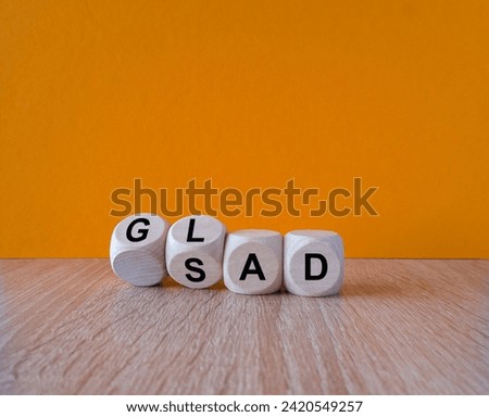 Glad or sad symbol. Turned wooden cubes and changes the word Sad to Glad. Beautiful orange background, wooden table. Copy space. Business motivational and glad or sad concept.