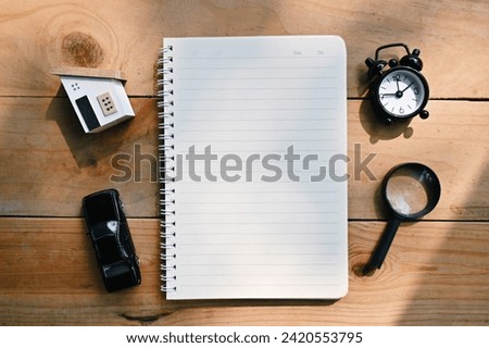 close up notebook, wood house, toy car, alarm clock and magnifying glass on table, to do list and mission goal wallpaper background concept