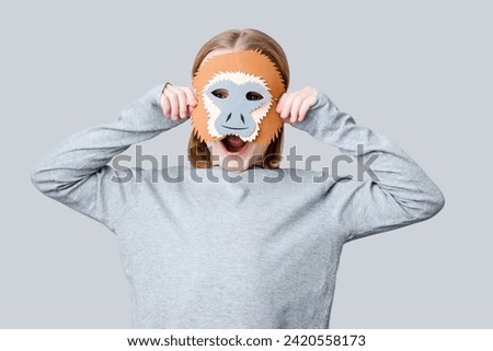 A boy playing in a monkey mask on a gray background. Child handmade mask fun for Halloween holiday or carnival. High quality photo