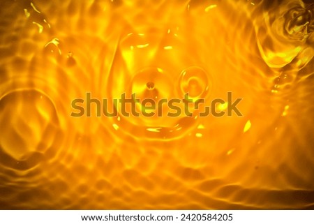 Picture of the surface of the water rippled with orange rays, glittering lights, and air bubbles.