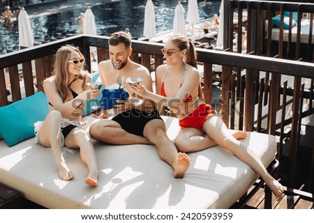 A cheerful group of friends relaxes with cocktails by the pool.