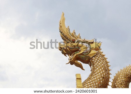Golden Naga statue with sky in the background Royalty-Free Stock Photo #2420601001