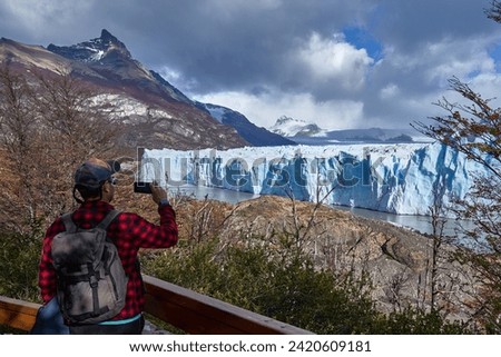 tourist taking a photo with her smartphone at the perito moreno glacier