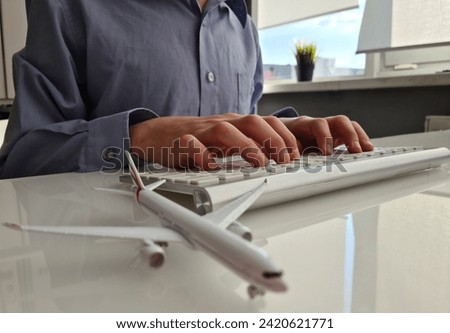Airplane and persons on laptop keyboard. Introduction to global aviation related things can be done online at hand Royalty-Free Stock Photo #2420621771