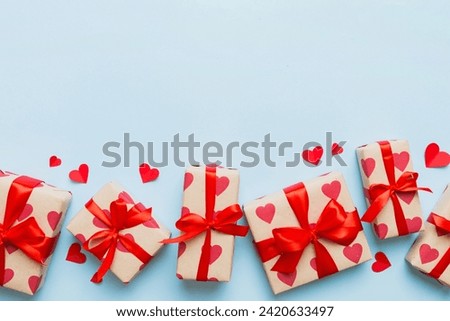 Top view photo of valentine day decorations gift box with red ribbon bow on colored background. Holiday gift boxes with top view.