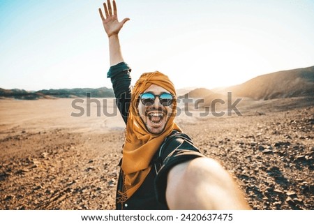 Happy traveler with backpack taking selfie picture with smart mobile phone outdoors - Cheerful guy smiling on the top of the mountain - Hiker traveling in rocky desert - Travel technology life style