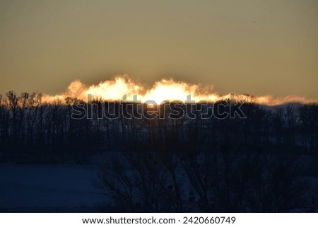 sun rising above the snow covered hill in a bright orange fire light tone