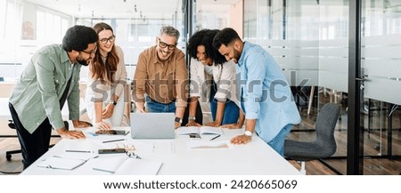 A panoramic view of a motivated team intensely focused on a computer screen, capturing the essence of a strategic work session in a contemporary, light-filled office. Diverse work group brainstorming Royalty-Free Stock Photo #2420665069