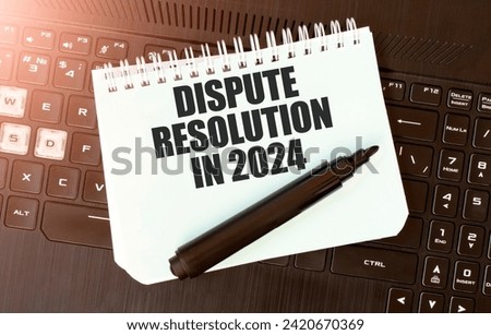 White paper sheet with text DISPUTE RESOLUTION IN 2024 on the black laptop Royalty-Free Stock Photo #2420670369