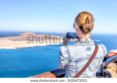 Lanzerote, Spain - December 24, 2023: A woman taking a picture of the landscapes of the island of Lanzerote from the Mirador Del Rio viewpoint in Spain's Canary Islands

