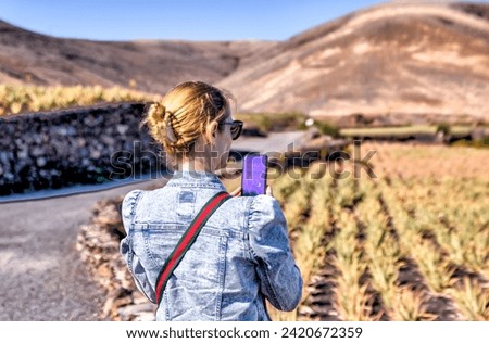 Lanzerote, Spain - December 24, 2023: A woman taking a picture of a field of aloe vera plants on the island of Lanzerote in Spain's Canary Islands
