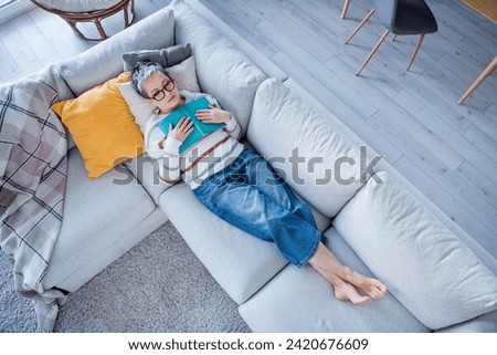 Full size high angle view photo of calm peaceful aged lady fell asleep couch hold opened book spacious apartment inside