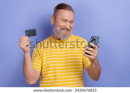 Photo of positive aged man use smart phone online shop order hold debit card isolated on violet color background