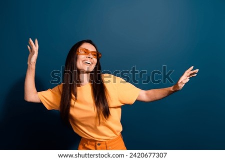 Portrait of satisfied lovely woman wear stylish t-shirt in sunglass dancing at summer party isolated on dark blue color background