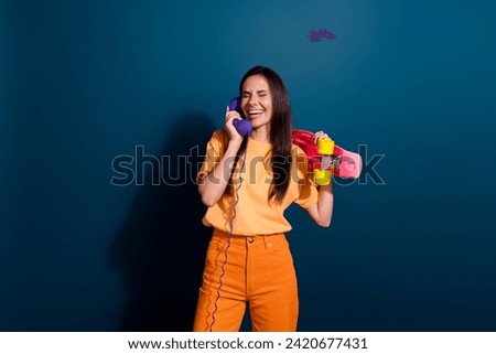 Photo of latin girl laughing when listen humor joking friends phone line holding pink skateboard isolated on dark blue color background Royalty-Free Stock Photo #2420677431