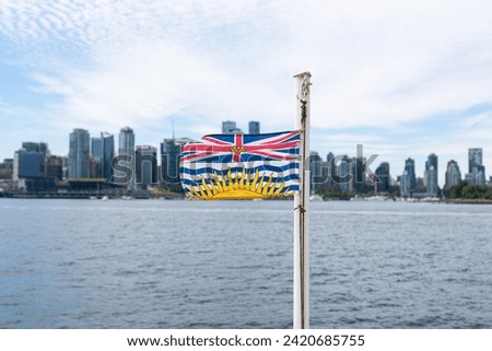 A British Columbia Flag flapping in the wind with the Vancouver Skyline in the background.