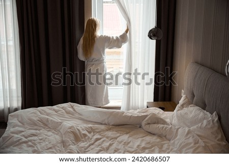 Woman standing in front of window in bedchamber after morning awakening Royalty-Free Stock Photo #2420686507