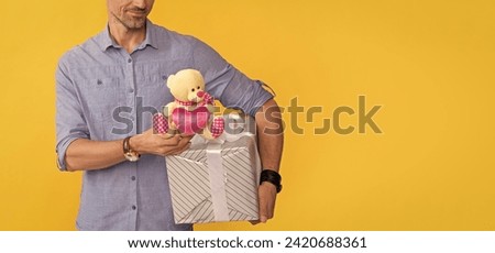 cropped mature man hold box and toy on yellow background, copy space, anniversary