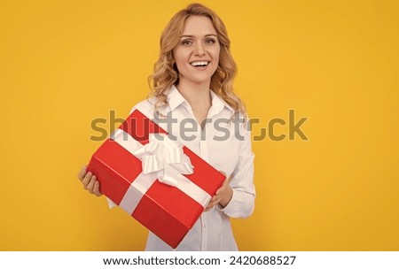 positive woman with big present box on yellow background