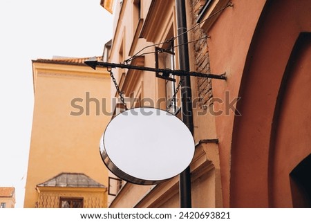 Mock up of a white blank empty oval vintage circle for cafe, restaurant name and logo, in an old town city. Blank white signboard on the wall.