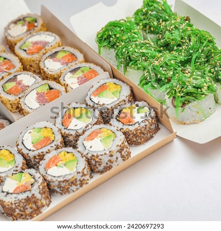 A photograph showing a box filled with sushi placed next to another box containing various types of sushi. Royalty-Free Stock Photo #2420697293