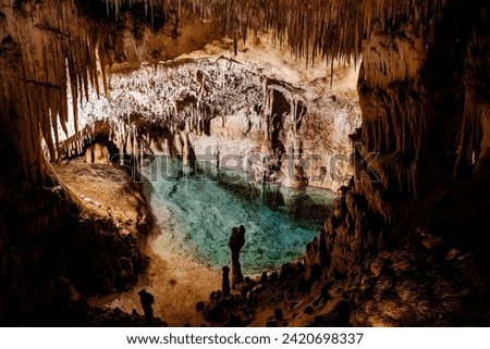 "Underground cave, stalactites, stalagmites, clear blue water pool, illuminated." Royalty-Free Stock Photo #2420698337