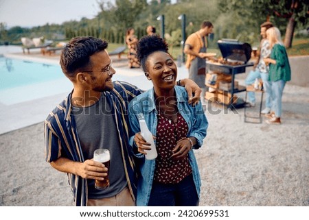 Happy multiracial couple enjoying on a BBQ party with their friends at poolside.  