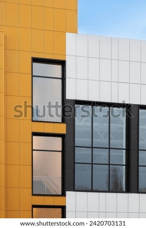 Fragment of a new commercial complex. Yellow-brown modern ventilated facade with large windows. Part of an urban property. Vertical