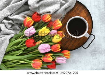 Colorful bouquet of tulips and a cup of coffee or hot tea on a tray - cozy hygge spring background Royalty-Free Stock Photo #2420721905