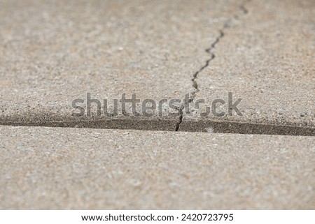 Concrete driveway cracked and settling. Home inspection, slab jacking and sidewalk repair concept. Royalty-Free Stock Photo #2420723795