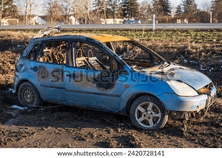 A burned car wreck near to highway Royalty-Free Stock Photo #2420728141