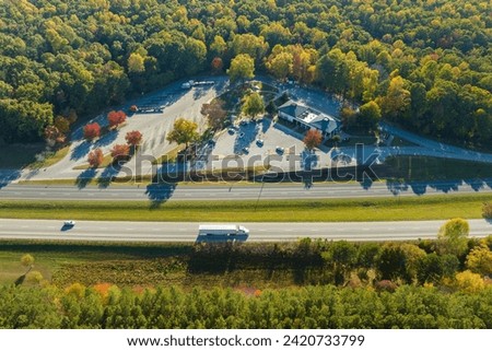 View from above of big parking rest area for cars and trucks near busy american highway with fast moving traffic. Recreational place during interstate travel Royalty-Free Stock Photo #2420733799