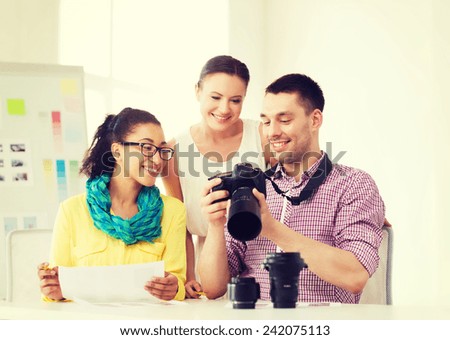 business, education, office and startup concept - smiling creative team with photocamera working in office