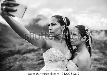 portrait of two young newly married women taking a selfie with their phone and walking in the open air.