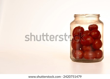 plum tomatoes in a glass jar on white background