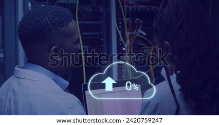 Image of cloud with uploading over african american man working on laptop in server room. network, programming, computers and technology concept digitally generated image.