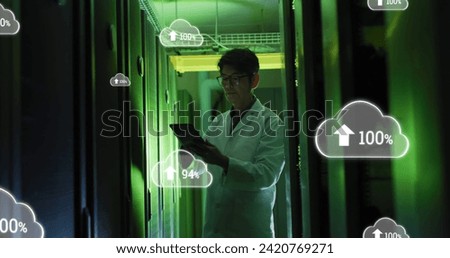 Image of clouds with uploading over asian man working in server room. network, programming, computers and technology concept digitally generated image.