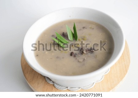 a close up of a bowl of green bean porridge and black sticky rice doused in coconut milk Royalty-Free Stock Photo #2420771091