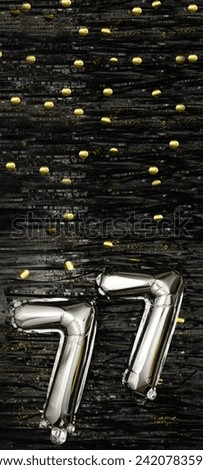 Greeting celebration seventy-seven years birthday. Anniversary number 77 foil silver balloon on black background. Happy birthday, congratulations concept. golden confetti. Vertical banner