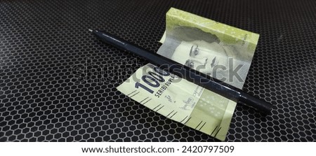 Black ballpoint with a price of one thousand rupiah in Indonesia on a base with a black motif